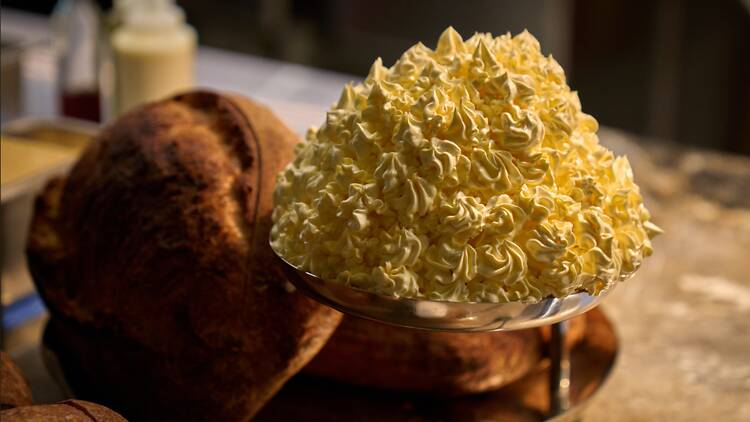 A plate of butter with a loaf of bread beside it 