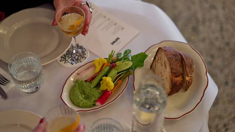 A restaurant table of starters with vegetables and bread.