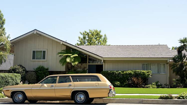 A station wagon parked in front of the Brady Bunch house.