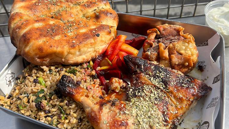 Charcoal chicken and sides on a silver platter.