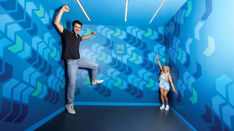 A man and a woman try out the Ames room at the Museum of Illusions 