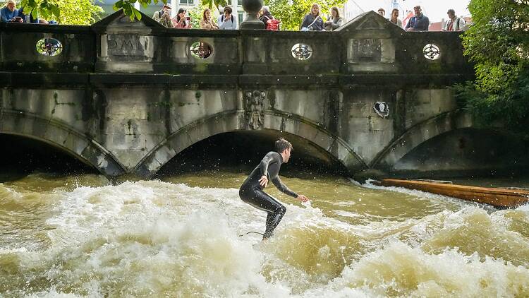 Surfers on the Eisbachwelle, a large river wave in the middle of Munich Surfers on the Eisbachwelle, a large river wave in the middle of Munich