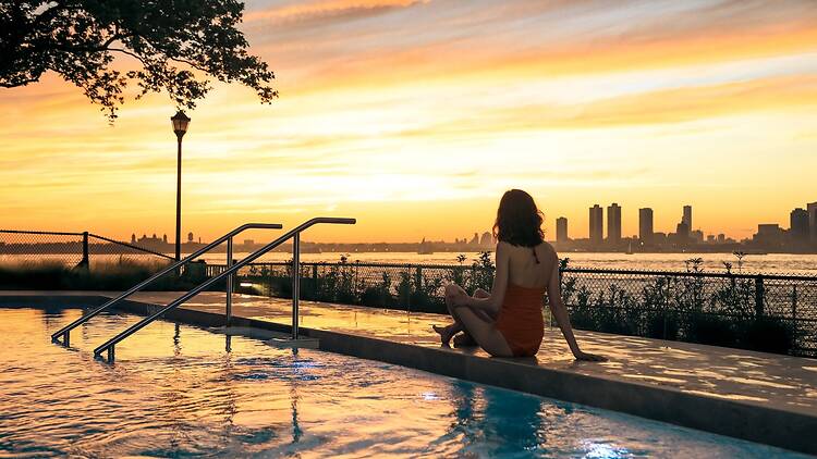 QC Spa Sunset at the pool at QC spa with a woman sitting on the concrete edge of the pool