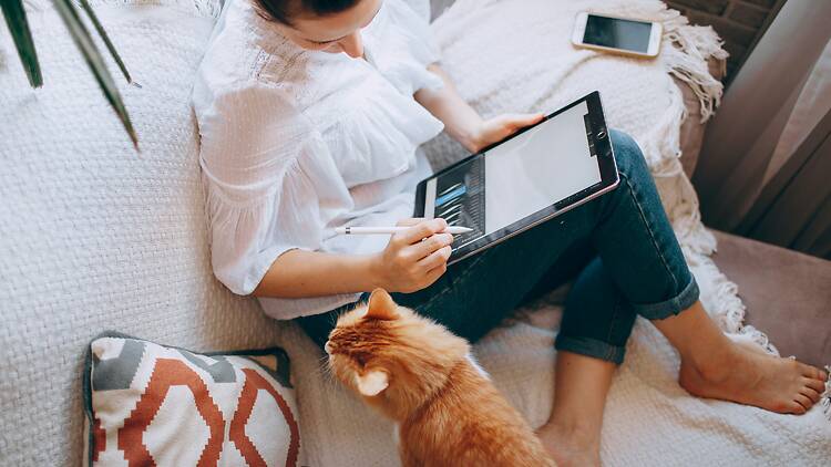 woman working from home woman-in-white-long-sleeve-shirt-and-blue-denim-shorts-sitting-on-bed-using-tablet-computer