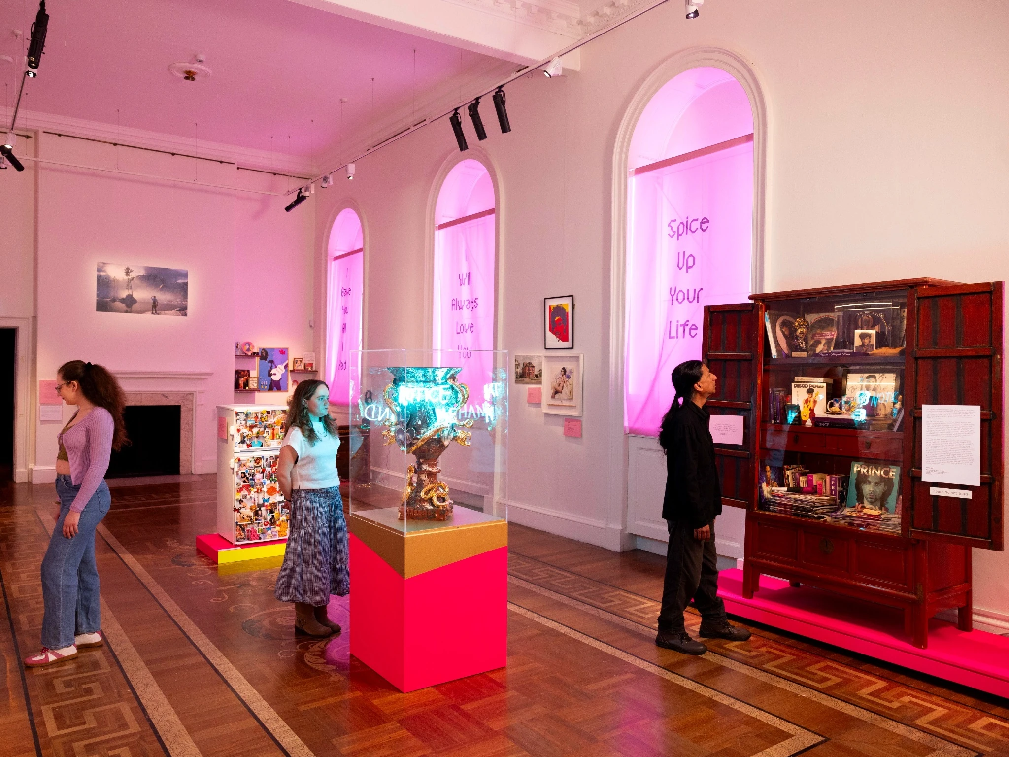 Three visitors looking at exhibits in Somerset House&rsquo;s fandom exhibition, &lsquo;Holy Pop!&rsquo;