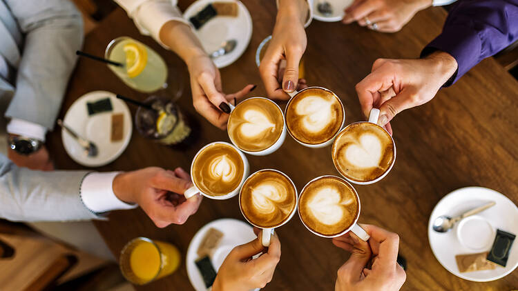 Group of friends cheering with coffee cups in cafe Group of friends cheering with coffee cups in cafe