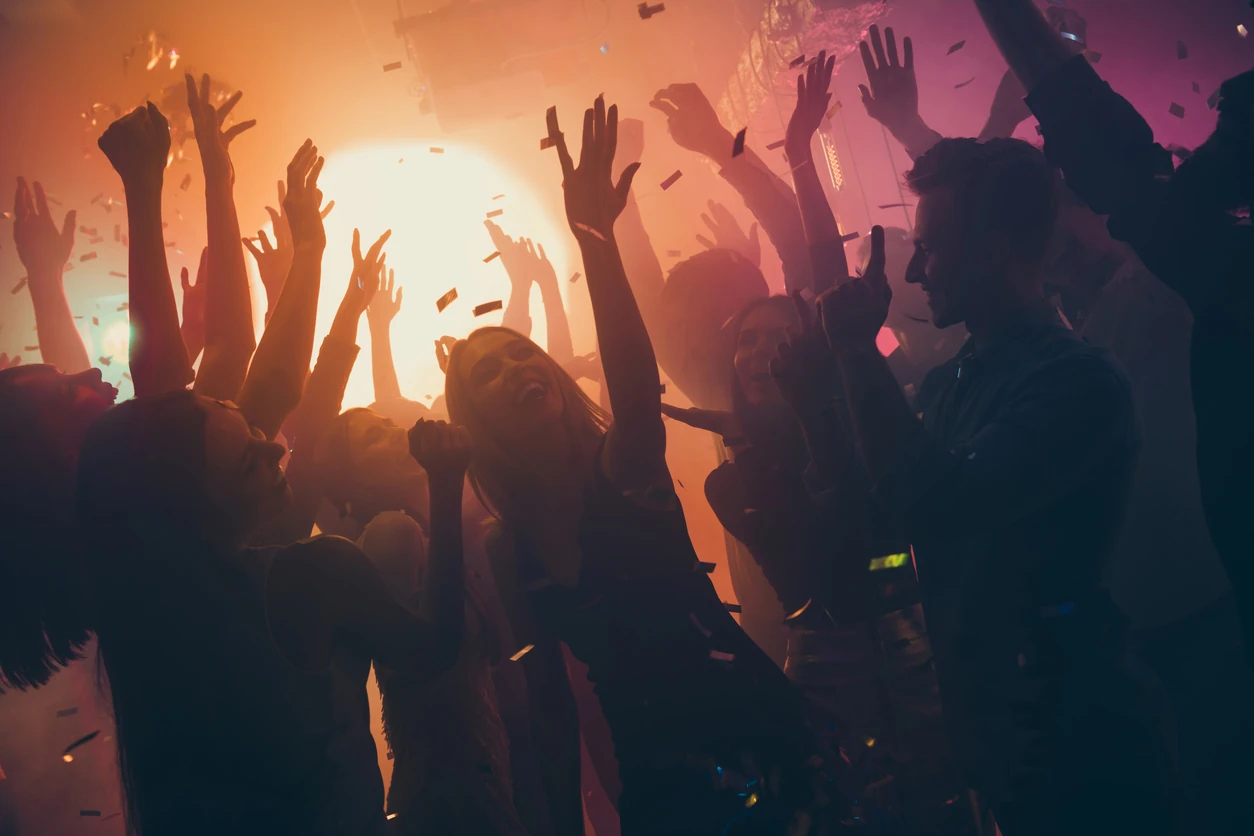 Photo of many party people buddies dancing yellow lights confetti flying everywhere nightclub event hands raised up wear shiny clothes