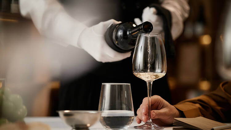 Caucasian Sommelier Pouring White Wine for Middle Aged Woman during Tasting Caucasian Sommelier Pouring White Wine for Middle Aged Woman during Tasting