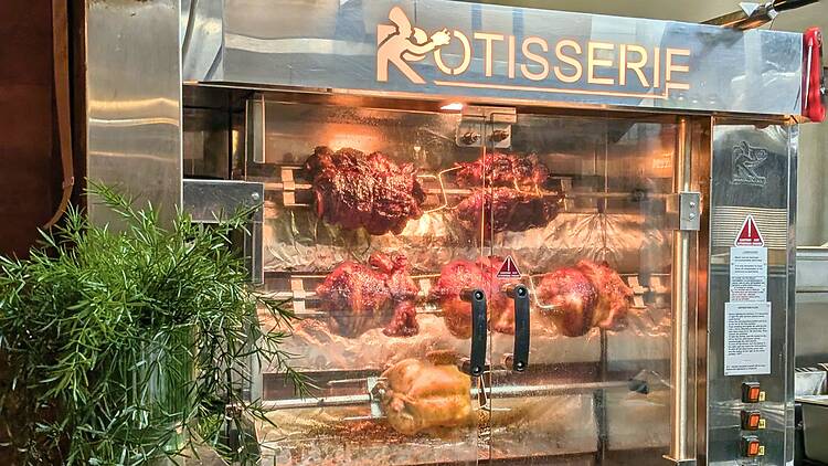 a rotisserie with chickens and rolls of pork on the spit