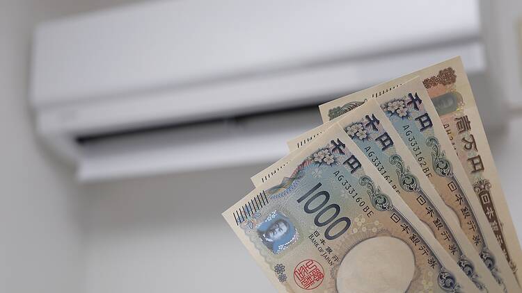 Person holding yen in front of an AC unit Person holding yen in front of an AC unit