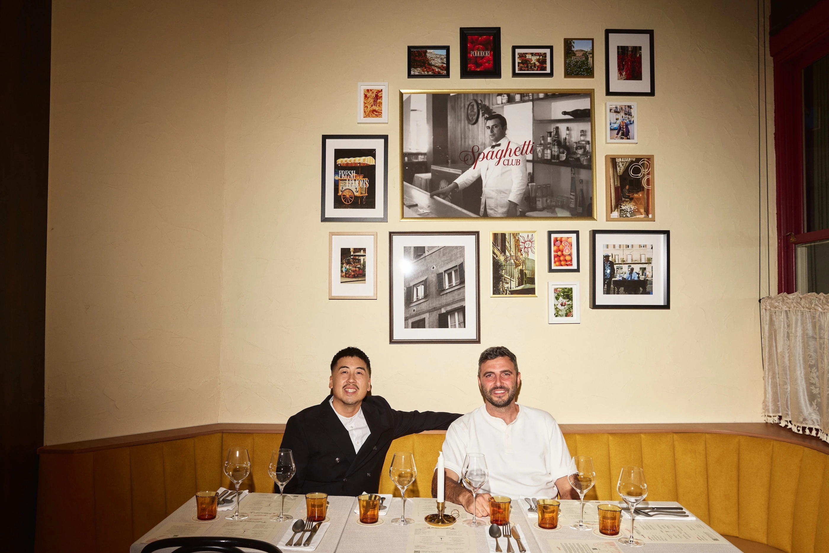 Spaghetti Club's Thai Ho and Lucas Gugliandolo sit in front of a wall filled with photos