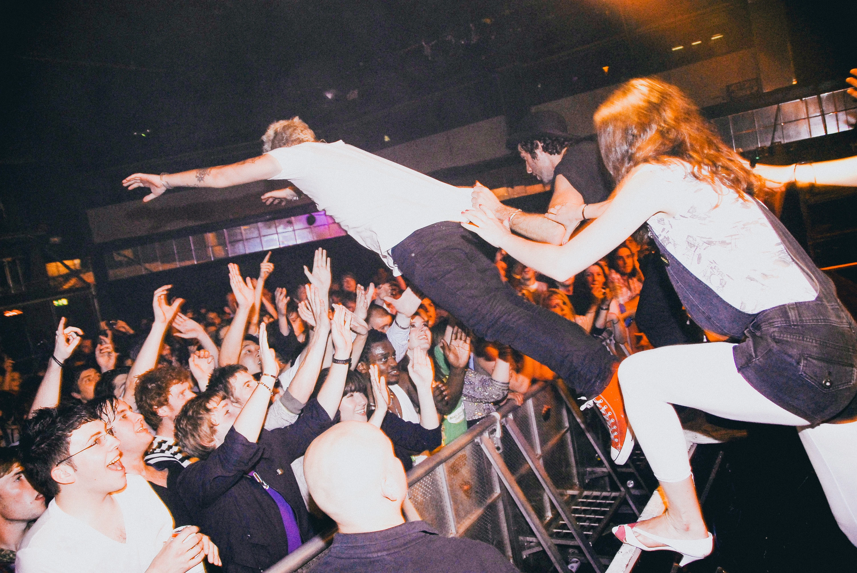 Kid Harpoon leaning off the stage at the Mean Fiddler to a crowd with their arms held up