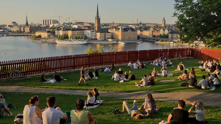People relax on a grassy hill overlooking Stockholm’s waterfront and historic skyline at sunset, capturing the kind of local, experience-driven moments highlighted in the Time Out Stockholm launch article People relax on a grassy hill overlooking Stockholm’s waterfront and historic skyline at sunset, capturing the kind of local, experience-driven moments highlighted in the Time Out Stockholm launch article