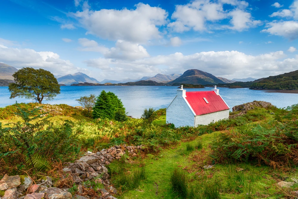 A pretty red roofed croft on the shores of Loch Shieldaig on the Applecross Peninsula in the Highlands of Scotland