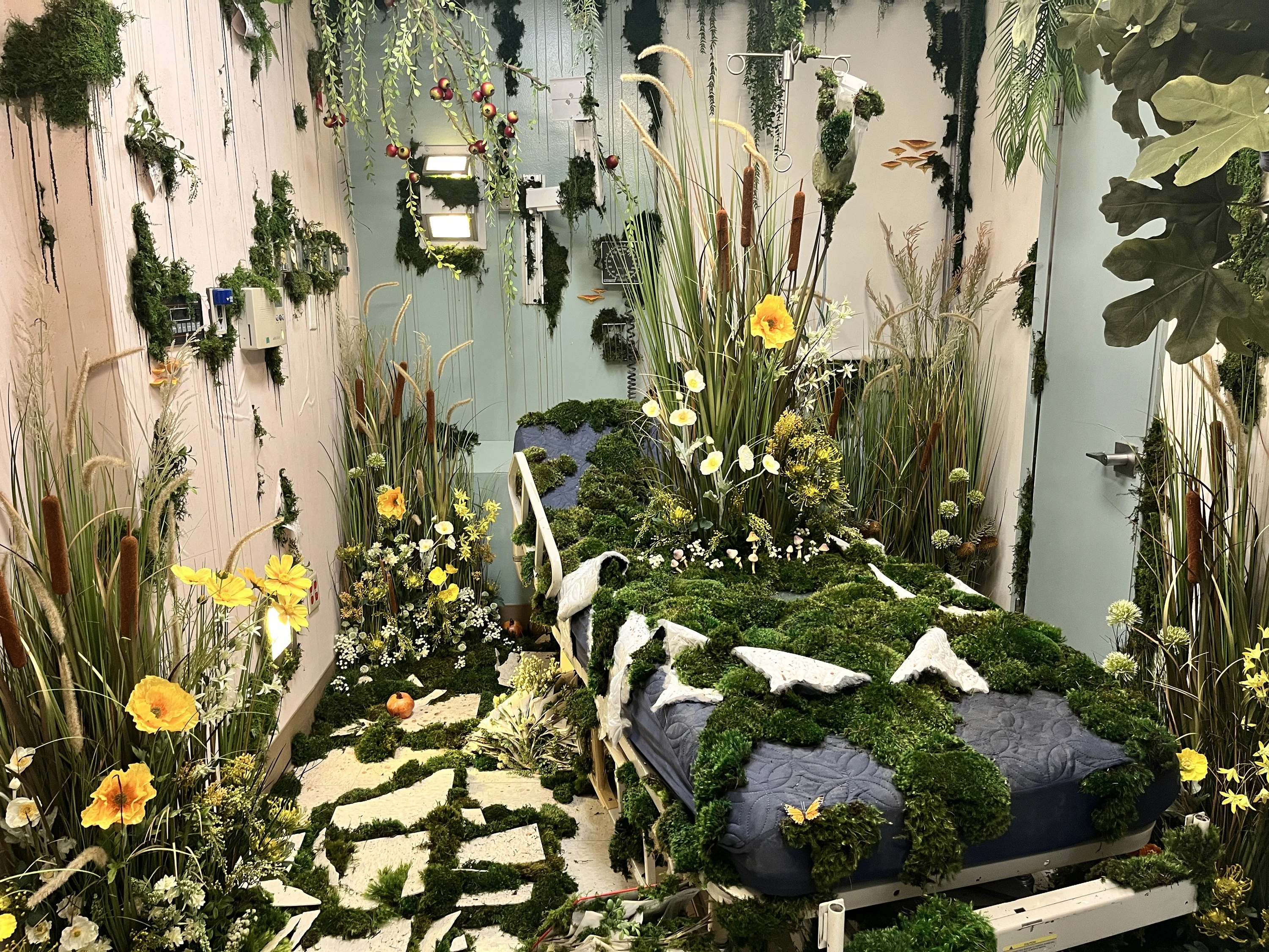 A hospital room filled with flowers and moss at Hospital of Emotions.