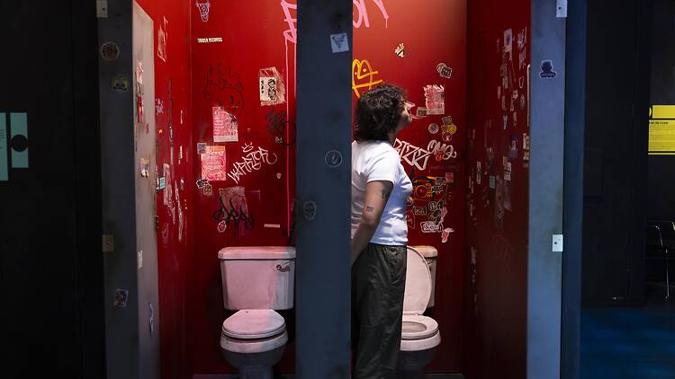Lost Music Venues display,V&A South Kensington, London, UK - 27 MAY 2026 A person inside a recreation of a music venue toilet cubicle in the V&A