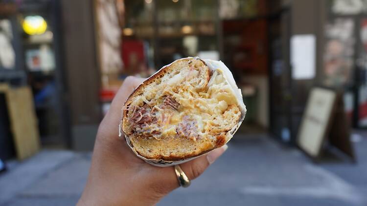 A person holding a Pastrami Reuben