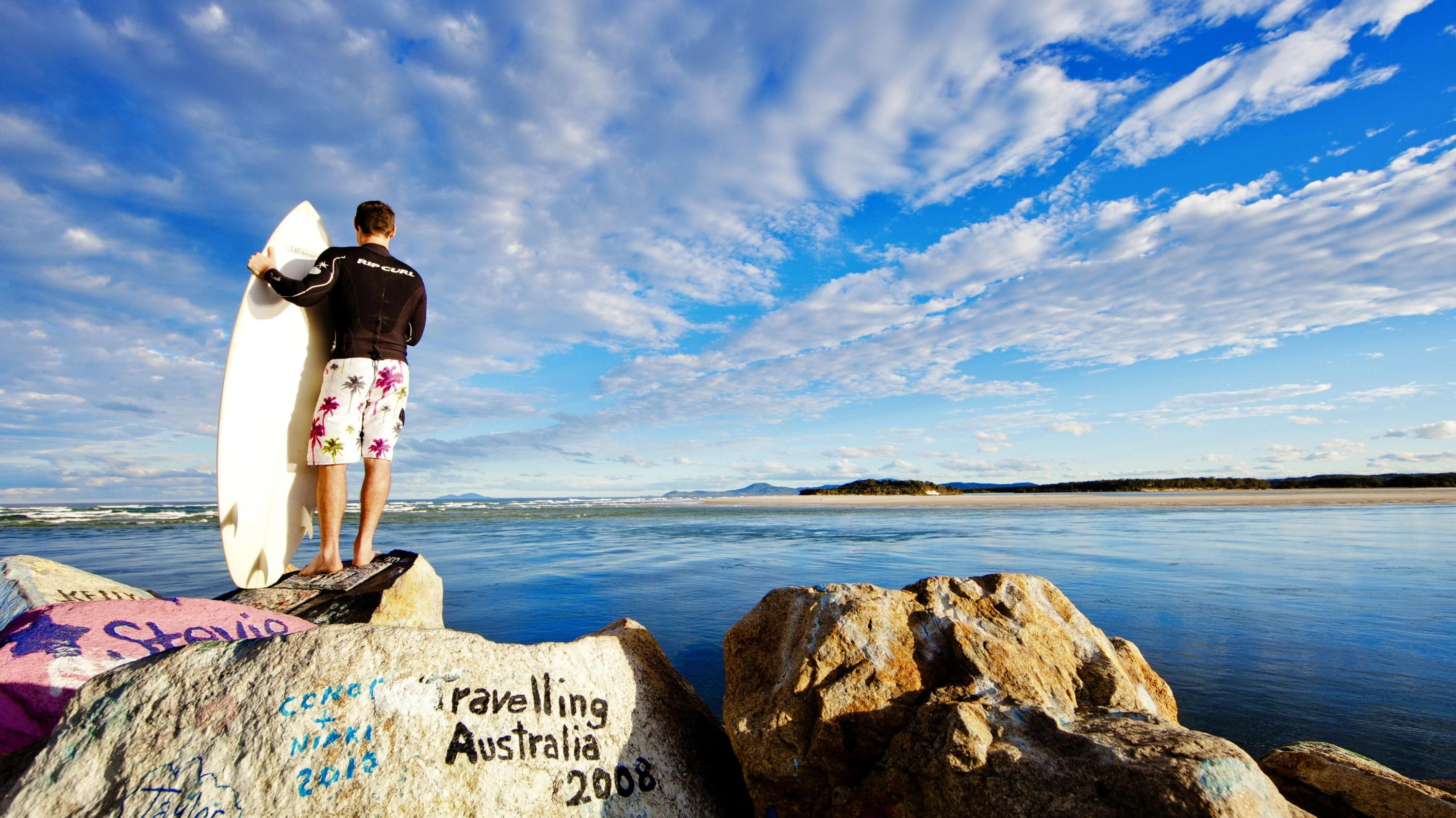 Surfer standing on top of part of the Nambucca Heads V-wall, an outdoor artistic graffiti gallery, North Coast