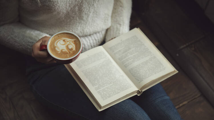 Una mujer leyendo con un café de especialidad Una mujer leyendo con un café de especialidad