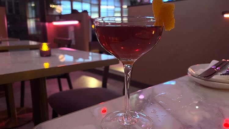 A reddish cocktail on a marble table
