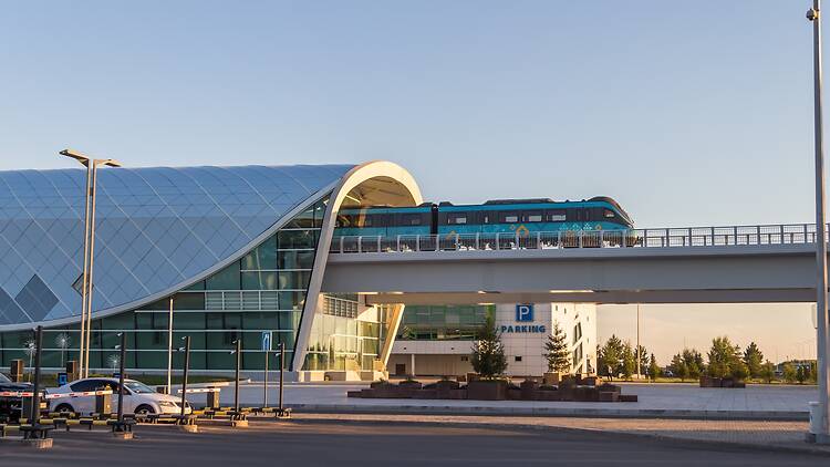 Astana, Kazakhstan (Qazaqstan), 21 jule 2025 - Light rail transport LRT leaves the Astana airport station. A blue train with a beautiful pattern stands on the overpass. 