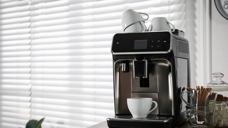 Modern coffee machine with cup in office Modern coffee machine