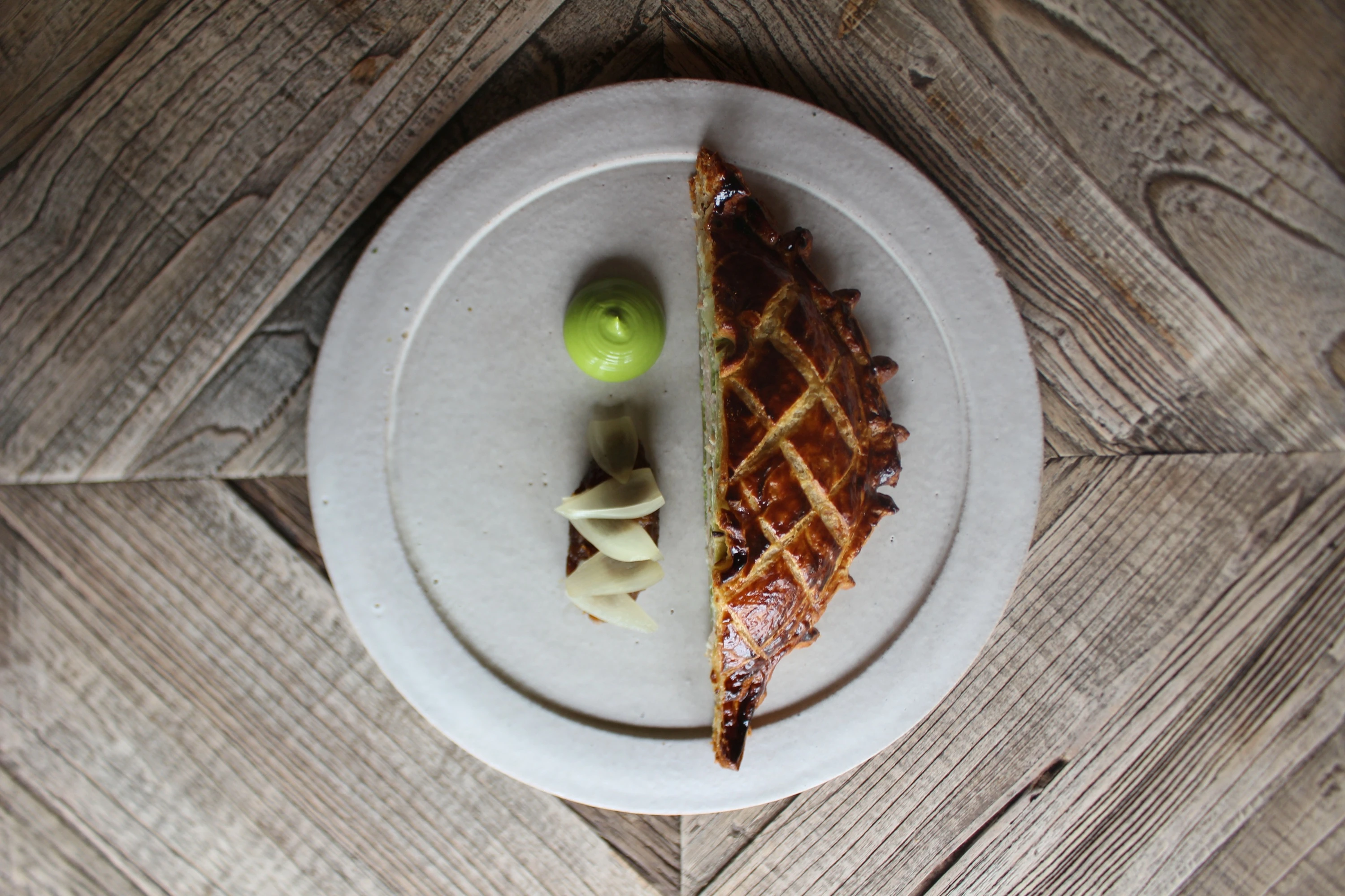 A Guinea fowl pie with green sauce and sliced garnish 
