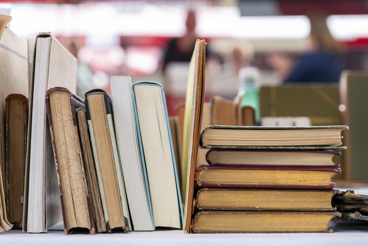 A diverse collection of second-hand books displayed on a market table at the annual book fair. Fiction, non-fiction, and classics await eager readers searching for hidden literary treasures.