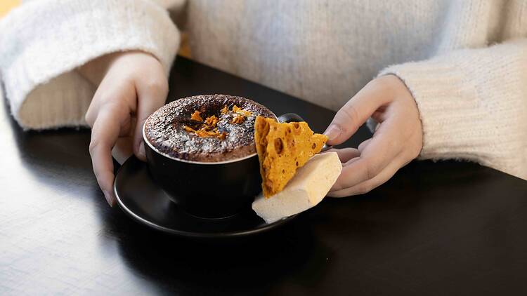 Ballarat Winter Festival Hot Choc Showdown La Miette Patisserie person holds cup of hot chocolate served with honeycomb