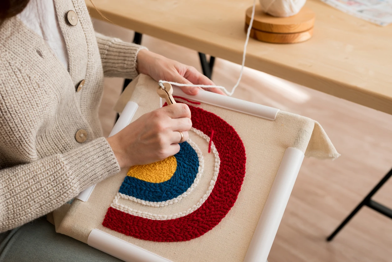 Close up of woman creating a handmade decoration for home. Female pushing the punchneedle straight down into the fabric. Hobby, DIY, handycraft concept. New trend in embroidery Punch needle.