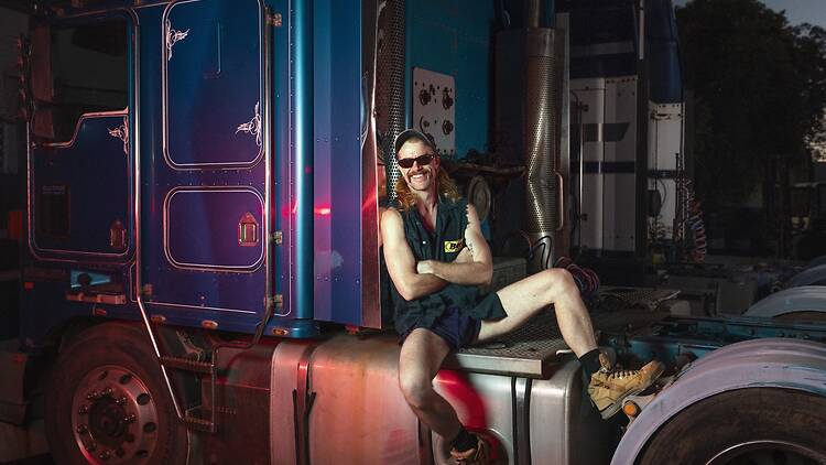Jonny Hawkins who plays Bev in Truck Driver man wear sunglasses, boots sitting on a truck