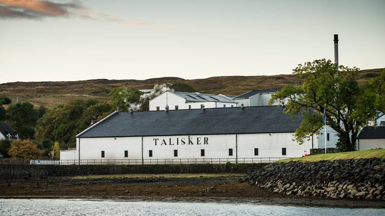 Talisker Distillery A distillery building on the water in the middle of hills