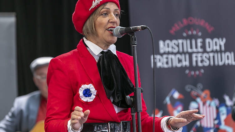 A French singer wearing a red beret and jacket performs at the Bastille Day French Festival 