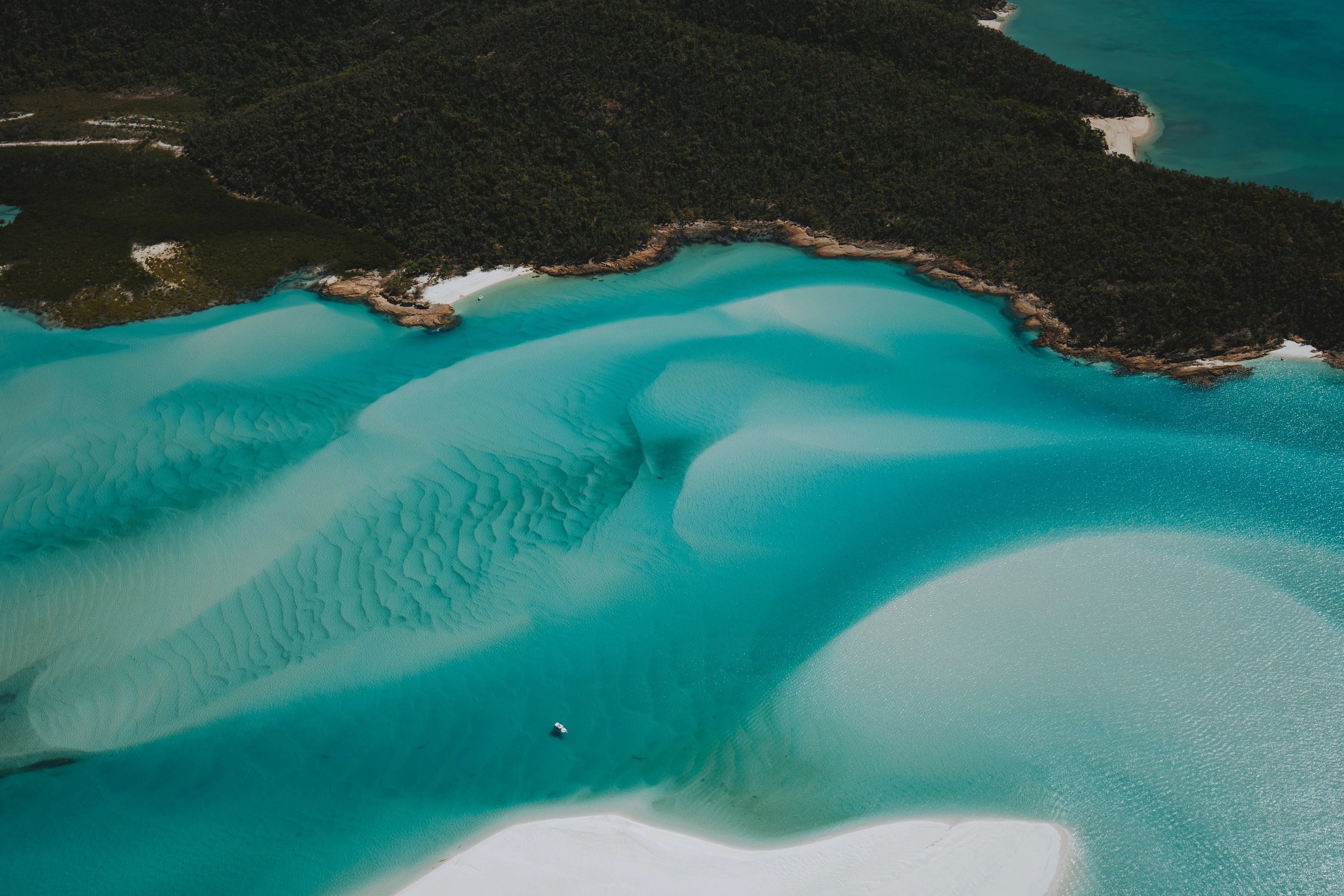 Aerial view of Hill Inlet sand formations with a small boat near the shoreline.