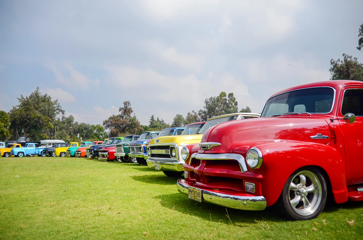 Vintage car show and exhibition of Chevrolet pick-up trucks and chevy cars outdoors. Red chevy classic vehicle parked in a retro event.