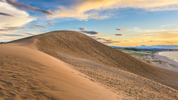 A sand dune with a sunrise sky