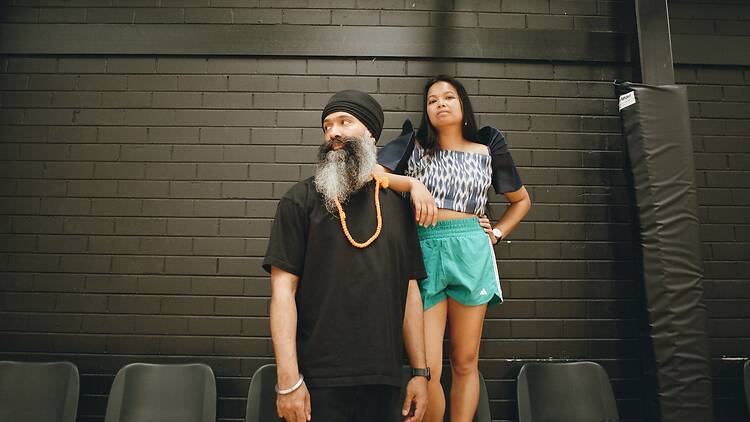 Co-producers of Archie Party: Sitara Tanglaw womna standing on chair, resting elbow on man's shoulder