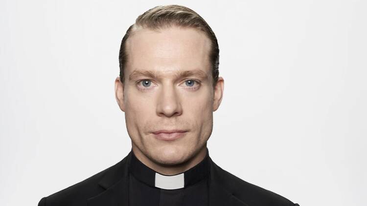 actor wearing a priest robe and collar