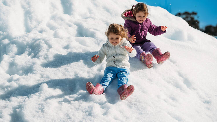 two girls play in the snow