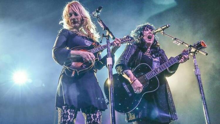 A close-up shot of two artists singing and playing guitar