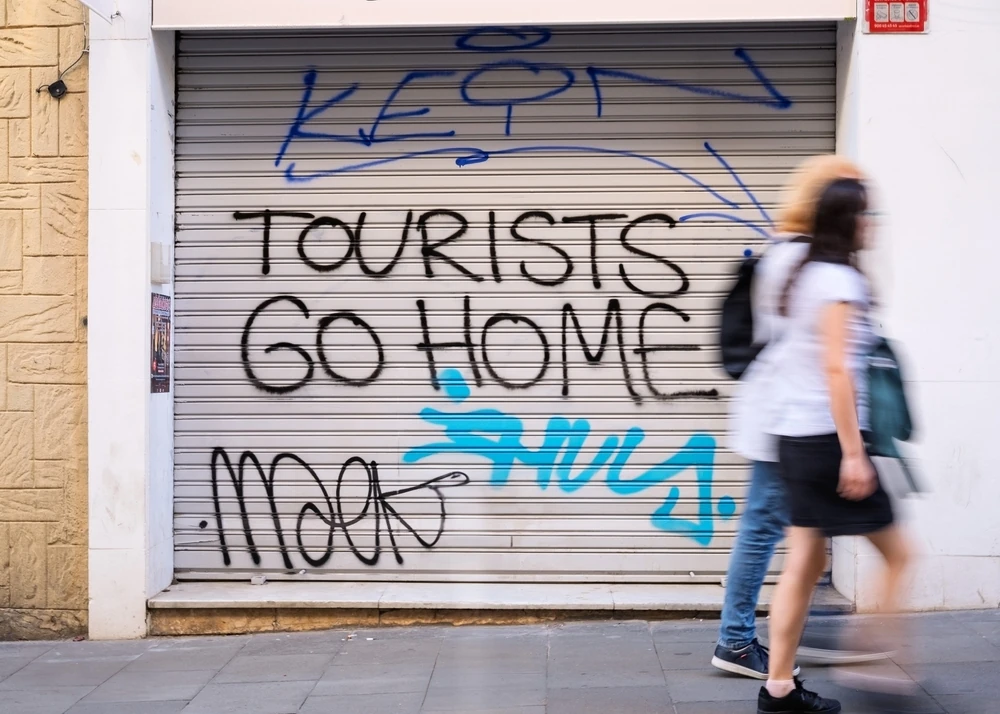 Two people walk past anti-tourist graffiti in Barcelona