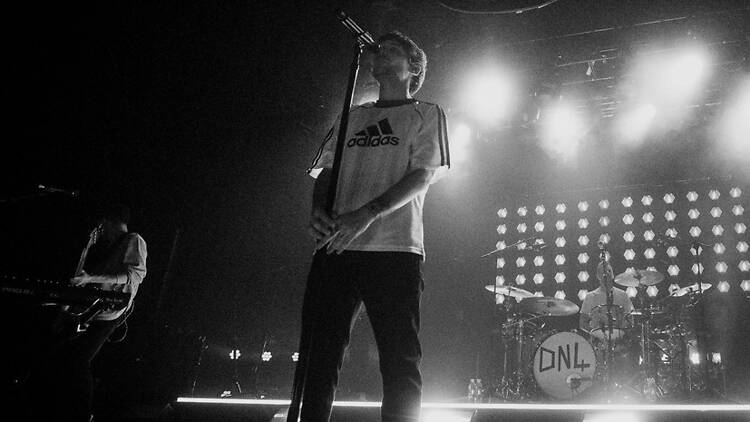 A black and white wide shot of a man singing onstage