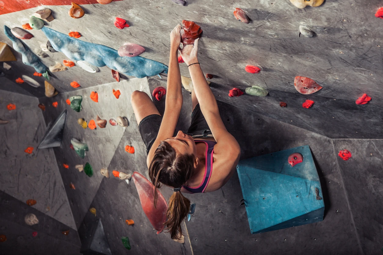 Young woman training on practice climbing wall indoor