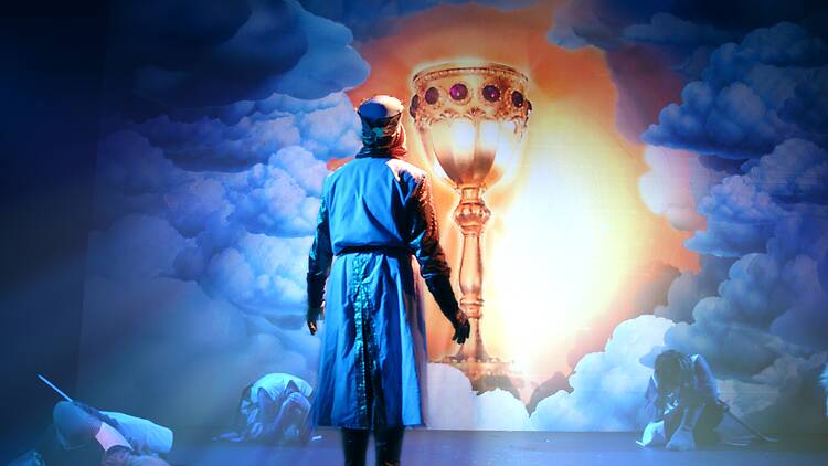 Spamalot A man dressed as a knight looking at a glowing cup