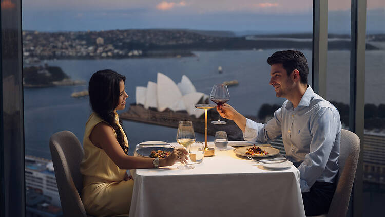 Altitude restaurant a couple cheersing at a restaurant table overlooking sydney opera house