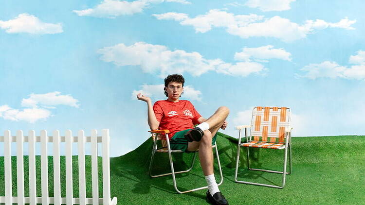 A wide shot of a man sitting in a fold-up chair
