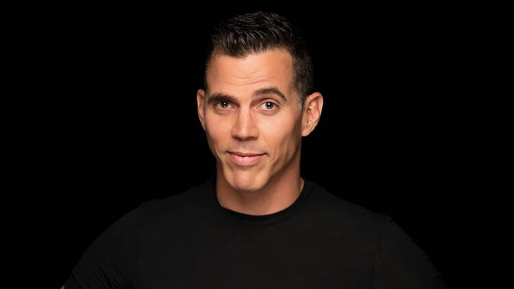A medium close-up shot of a man in black standing in a black background A medium close-up shot of a man in black standing in a black background