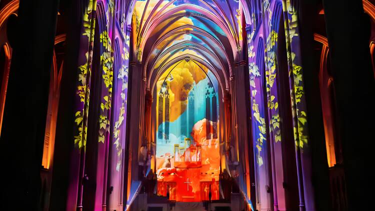 A wide shot of an interior of a cathedral illuminated in different colors