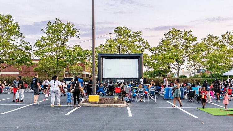 A wide shot of a large group of people gathered in front of a projected screen A wide shot of a large group of people gathered in front of a projected screen