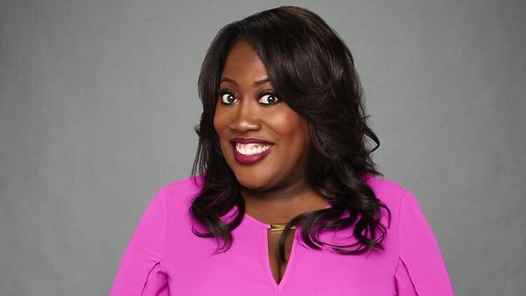 A medium close-up shot of a smiling woman wearing a bright pink dress against a gray background A medium close-up shot of a smiling woman wearing a bright pink dress against a gray background